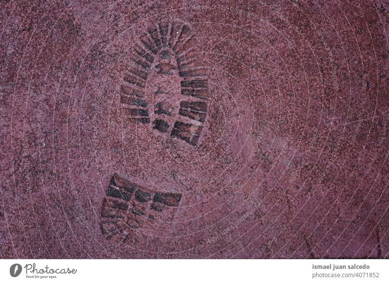 Fußabdruck auf dem roten Grund, strukturierter Hintergrund Fußspur drucken Boden Straßenbelag Textur Schuhdruck Bahn roter Hintergrund alt abstrakt