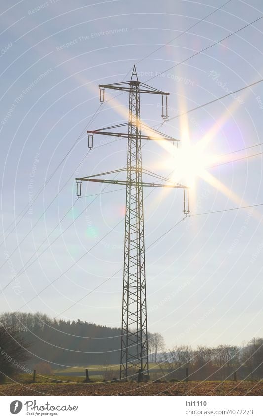 Strommasten in der Landschaft mit einem Sonnenstern am Himmel Energiewirtschaft Elektrizität ernergieversorgung Transportweg Hochspannung Leitungen Oberleitung