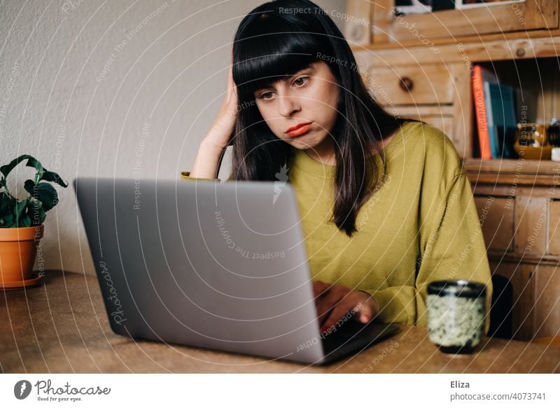 Frau sitzt gelangweilt zuhause vor dem Laptop Notebook gestresst Deadline frustriert überfordert genervt Homeoffice arbeiten online Studium Studentin digital