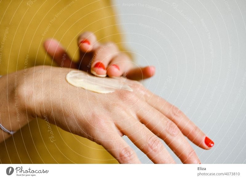 Eine frau cremt sich die Hände mit einer Handcreme ein eincremen Körperpflege trockene Haut Eincremen Hautpflege Kosmetik Creme Frau Nagellack Handpflege