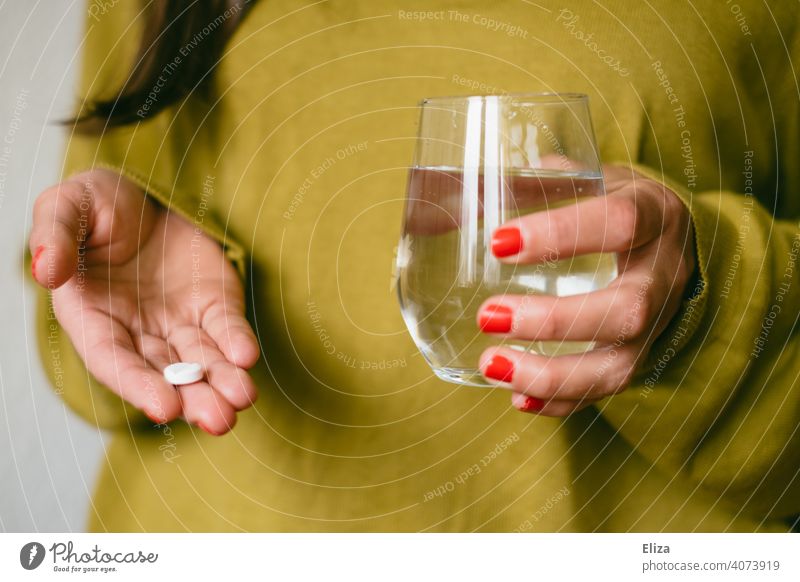 Frau hält eine Tablette und ein Glas Wasser in den Händen Schmerztablette Medizin Medikament Krankheit Behandlung Kopfschmerzen Migräne Schmerzmittel