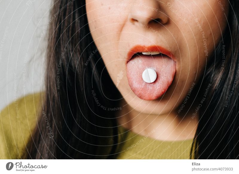 Frau mit Tablette auf der Zunge. Medikamenteneinnahme. einnehmen Medizin Schmerztablette Mund Behandlung Nahaufnahme weiß Sucht medikamentenmissbrauch