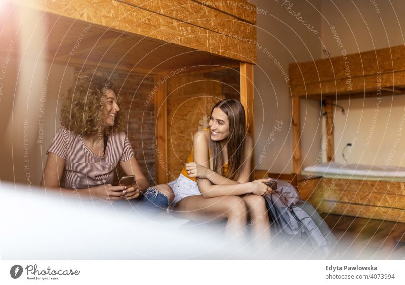 Junge Frauen sitzen in Etagenbetten und reden und lachen zusammen airbnb Miete reisen Tourist Herberge Gästehaus Ferien Reise flach Rucksack Backpacker besuchen