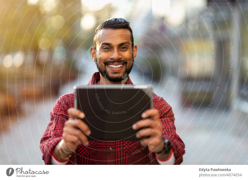 Junger Mann verwendet digitales Tablet im Freien in städtischer Umgebung Singhalesisch asiatisch Inder bärtig außerhalb Straße urban Stehen Großstadt Warschau