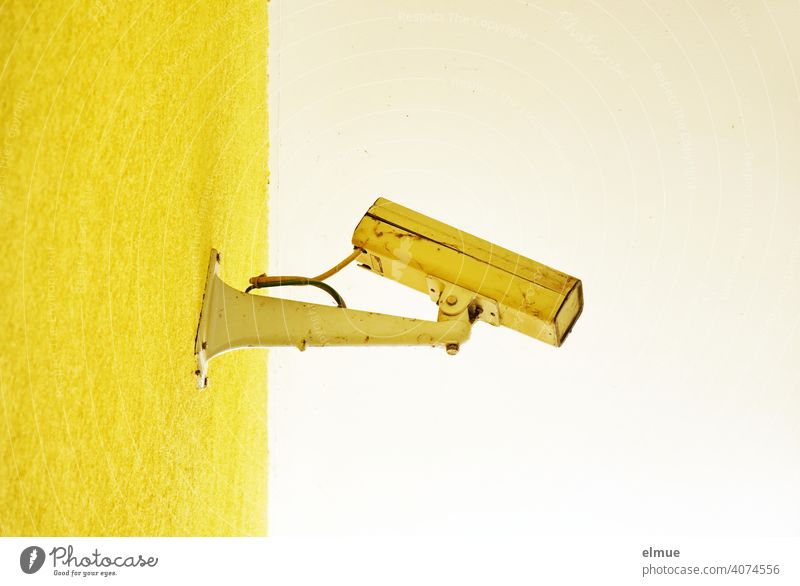 alte, kaputte, gelb angestrichene Überwachungskamera an einer gelben Wand / Kontrolle / Beobachtung Videoüberwachung Technik Aufsicht Technik & Technologie