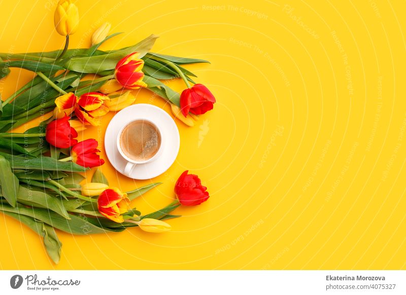 Schöne Frühling Frühstück auf Mütter oder Womans International Day 8 März. Blumenstrauß aus roten gelben Tulpen und Kaffeetasse auf leuchtend gelben Tisch Draufsicht. Flat Lay, Banner für Website, saisonale Flyer