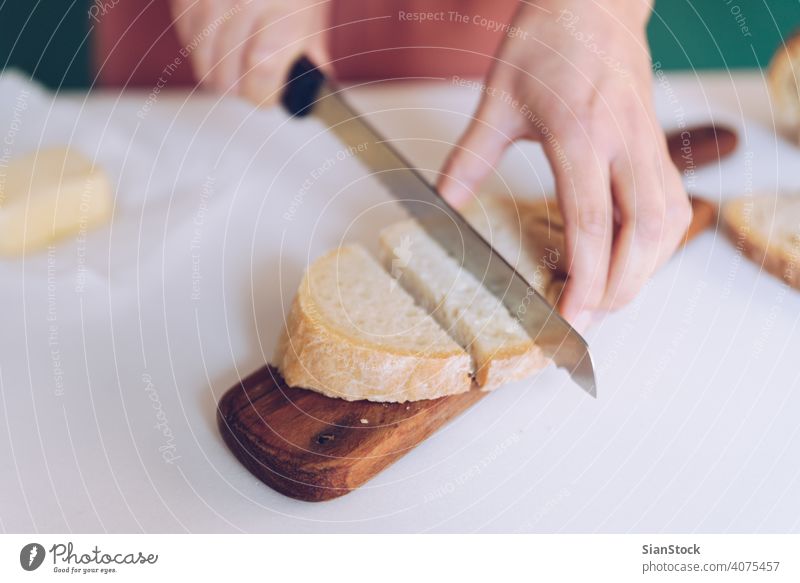 Frau schneidet Brot in der Küche geschnitten Schneiden Hände Frühstück Herstellung grün Hintergrund Kleid Murmel Essen zubereiten Koch heimwärts geröstet Löffel