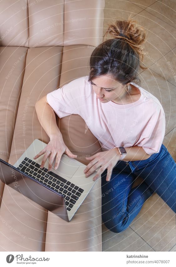 Junge Frauen arbeiten mit Laptop, während sie zu Hause auf dem Boden sitzen jung anhaben Attrappe T-Shirt lernen Schüler Lifestyle Draufsicht Stock Jeanshose