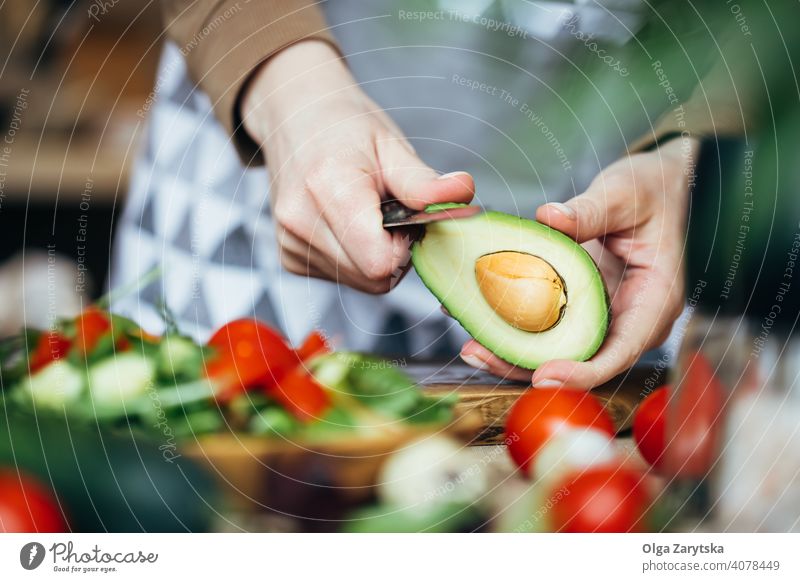 Frau schält eine Avocado. Salatbeilage sich[Akk] schälen Tomate Hand Mittelteil Selektiver Fokus abschließen Messer Herstellung hölzern Veganer Lebensmittel