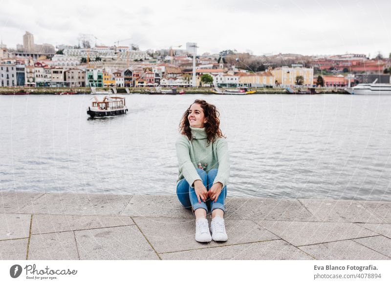 junge schöne Frau sitzt am Fluss bei Sonnenuntergang und genießt die Aussicht auf Porto. Reisen Konzept reisen Großstadt Sightseeing urban Kaukasier Menschen