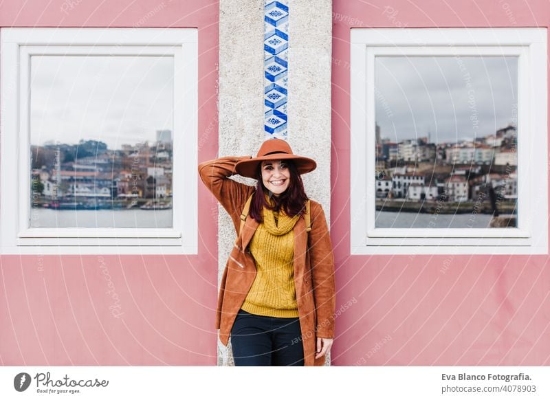 Porträt der jungen schönen Frau, die an der Mauer von Porto steht und einen modernen Hut trägt und die Aussicht genießt. Reisen Konzept reisen Fenster Wand rosa