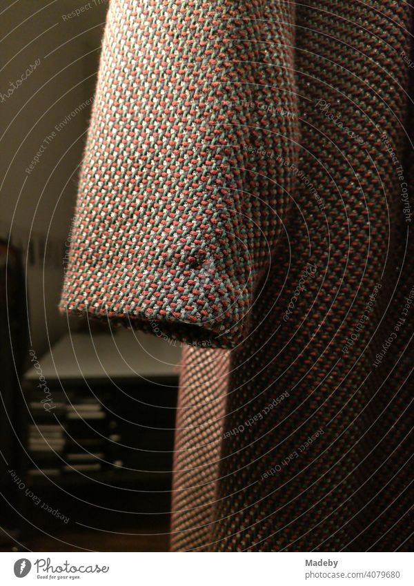Ärmel eines Mantel aus grobem Stoff mit eingewirkten bunten Fäden am Abend in einem Schaufenster im Nordend von Frankfurt am Main in Hessen Wintermantel Mode