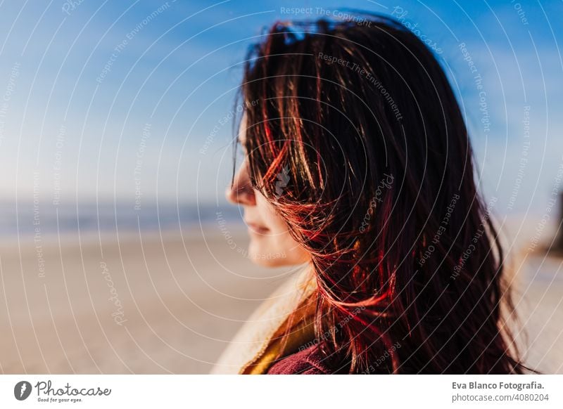 junge kaukasische Frau entspannt am Strand bei Sonnenuntergang. Selektiver Fokus auf Haare fliegen an einem windigen Tag. Urlaub und Entspannung Konzept Porträt