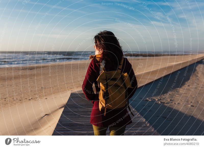 Backpacker junge kaukasische Frau am Strand bei Sonnenuntergang entspannen. zu Fuß durch hölzerne Passage oder Landebahn. Urlaub und Entspannung Konzept laufen
