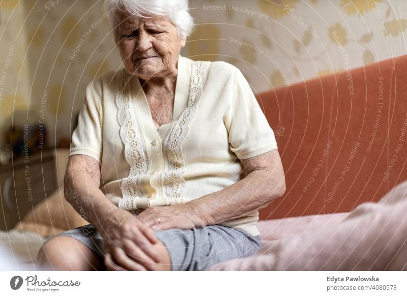 Seniorin mit Knieschmerzen Menschen Frau reif lässig Haus alt Alterung häusliches Leben Großmutter Rentnerin Großeltern in den Ruhestand getreten echte Menschen