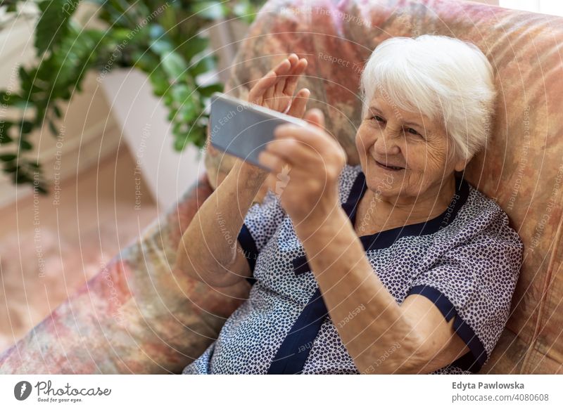 Ältere Frau benutzt Mobiltelefon zu Hause Lächeln Glück genießend Positivität Vitalität Freude Selbstvertrauen Menschen Senior reif lässig Kaukasier älter