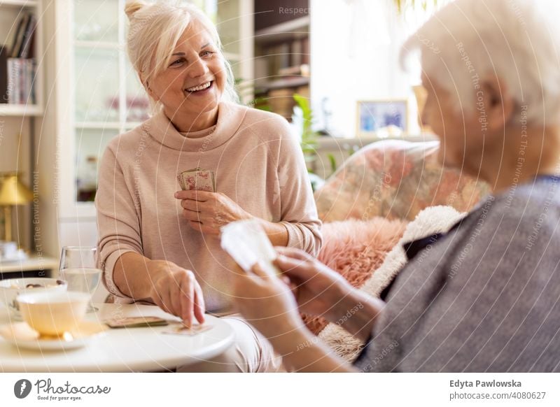 Ältere Frau und ihre erwachsene Tochter spielen Karten zu Hause Lächeln Glück genießend Positivität Vitalität Freude Selbstvertrauen Menschen Senior reif lässig