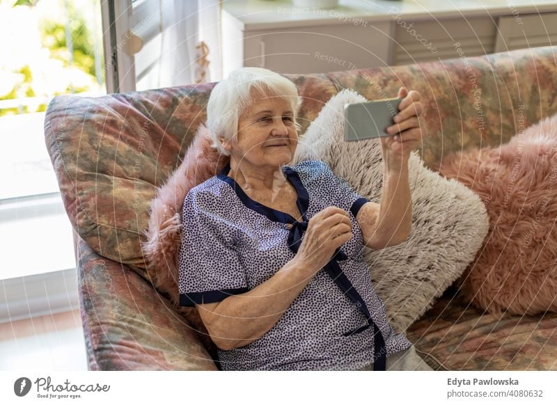 Ältere Frau benutzt Mobiltelefon zu Hause Lächeln Glück genießend Positivität Vitalität Freude Selbstvertrauen Menschen Senior reif lässig Kaukasier älter