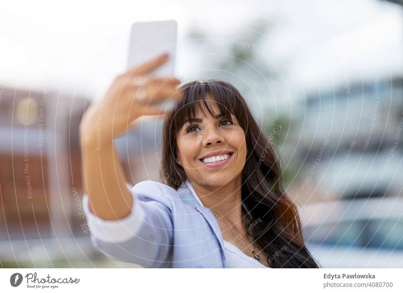 Attraktive junge Frau mit Smartphone in der Stadt hispanisch Latein Lächeln Sommer Spaß Freude Glück Fröhlichkeit Großstadt urban Mädchen Menschen Lifestyle