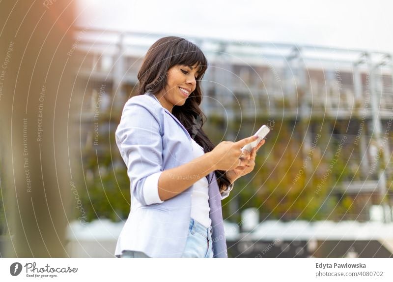 Attraktive junge Frau mit Smartphone in der Stadt hispanisch Latein Lächeln Sommer Spaß Freude Glück Fröhlichkeit Großstadt urban Mädchen Menschen Lifestyle