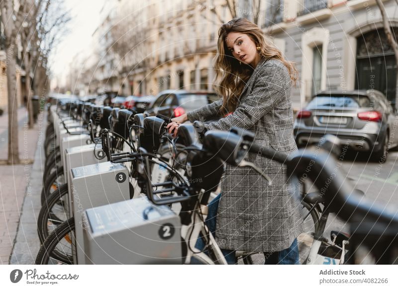 Dame wählt Mietfahrrad auf Parkplatz Öffentlich elegant Fahrrad Wochenende Freizeit Straße Freude Miete im Freien Reise Ausflug Frau Lifestyle Verkehr Urlaub