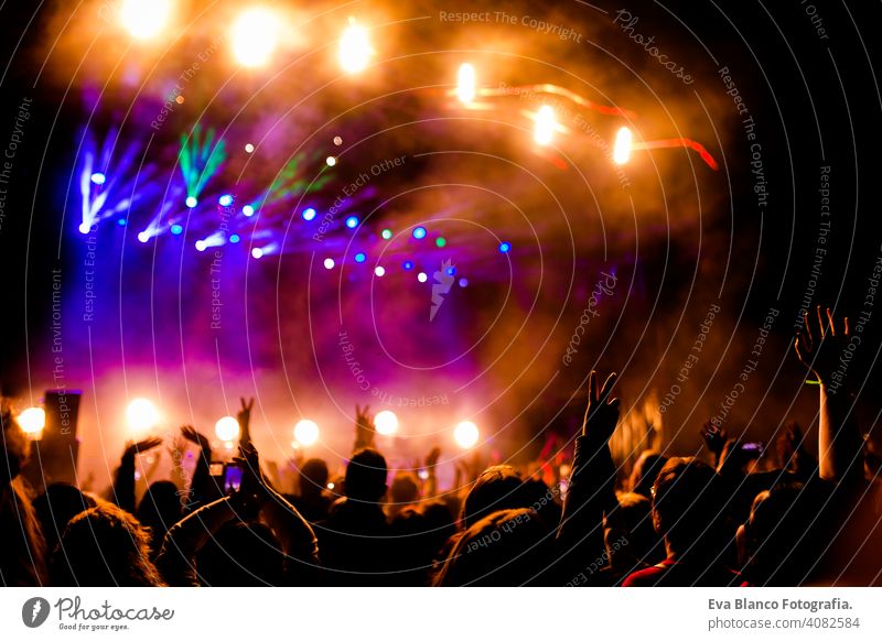 Bild von vielen Menschen, die sich an nächtlichen Aufführungen erfreuen, große, nicht wiedererkennbare Menschenmenge, die mit erhobenen Händen und Mobiltelefonen im Konzert tanzt. Nachtleben