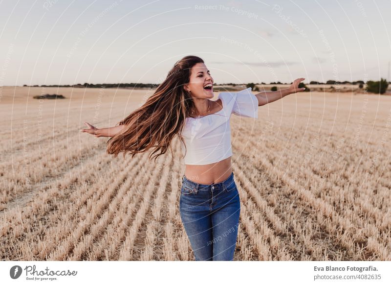Sommer Mädchen genießen die Natur auf gelben Feld. Schöne junge Frau tanzt im Freien. Lange Haare im Wind. Fröhlichkeit und Lebensstil. Rückansicht