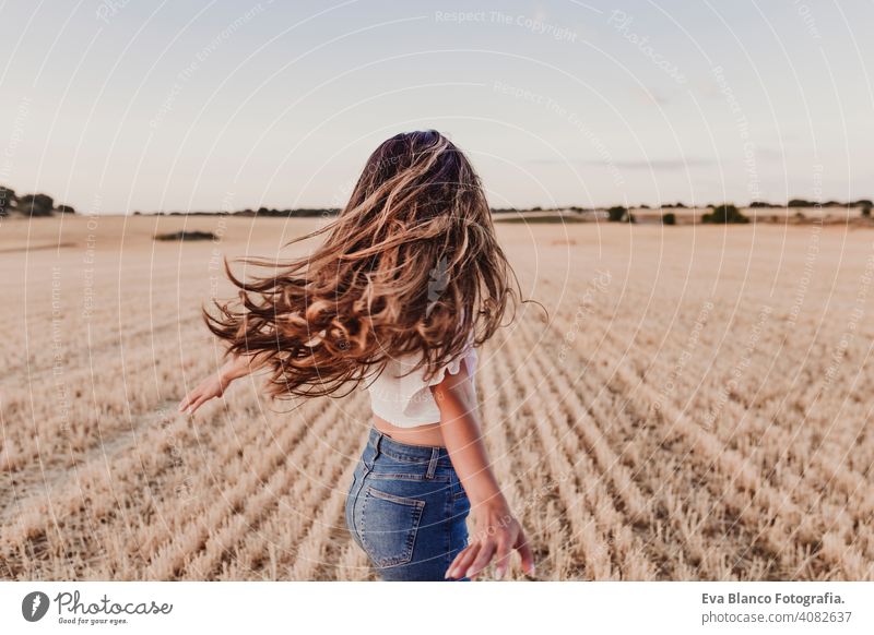 Sommer Mädchen genießen die Natur auf gelben Feld. Schöne junge Frau tanzt im Freien. Lange Haare im Wind. Fröhlichkeit und Lebensstil. Rückansicht