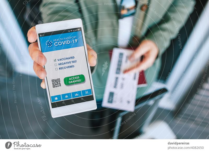 Frau zeigt covid Reisepass auf dem Smartphone an einer Flughafenkontrolle digitaler Grünpass Covid-Pass zeigend App Kontrolle Schriftstück unkenntlich Ausweis