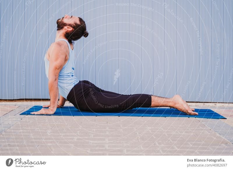 mann in der stadt, der yoga-sport betreibt. blauer hintergrund. gesunde lebensweise Blauer Hintergrund Yoga Mann Großstadt urban Lifestyle muskulös