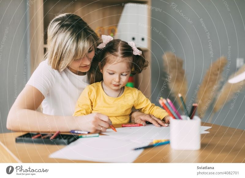Glückliche Mutter und Tochter zeichnen zusammen mit Buntstiften am Tisch im Zimmer. Gemeinsame Zeit, Kreativität, Bildung Mädchen Kind Mama Zusammensein