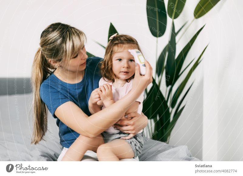 Eine besorgte Mutter überprüft die Temperatur ihrer Tochter mit einem elektronischen Thermometer Baby Beteiligung Überprüfung Eltern krank Kind Kindheit