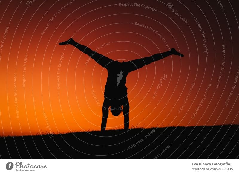 Silhouette des jungen Mannes in einem Park macht Yoga Sport. orange Himmel Hintergrund. gesunden Lebensstil. Rücklicht Konzentration positionieren Menschen