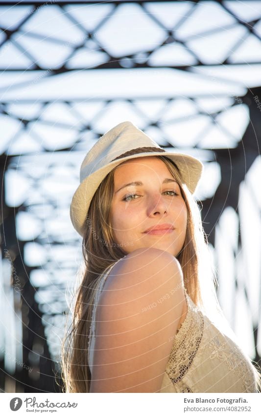 Porträt einer jungen Frau bei Sonnenuntergang im Freien Glück blond Hut blaue Augen Brücke Sommer sonnig Behaarung Fröhlichkeit Lifestyle Gesicht schön Spaß