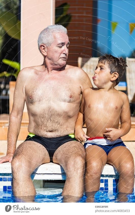 Opa und Enkel lächelnd auf einem Schwimmbad Seite 60s Erwachsener Junge Kaukasier heiter Kind Kindheit Kinder Mittäterschaft älter genießend Familie Vater
