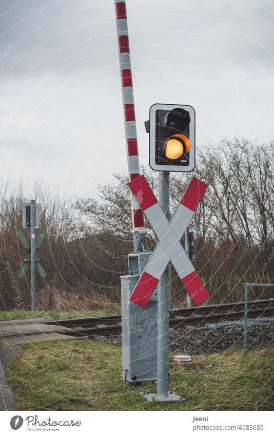 Auch wenn die Signalfarbe gelb anzeigt, muss man an den Bahnschienen warten Bahnschranke Schranke oben Bahnübergang Andreaskreuz Warnung gelb-orange Achtung