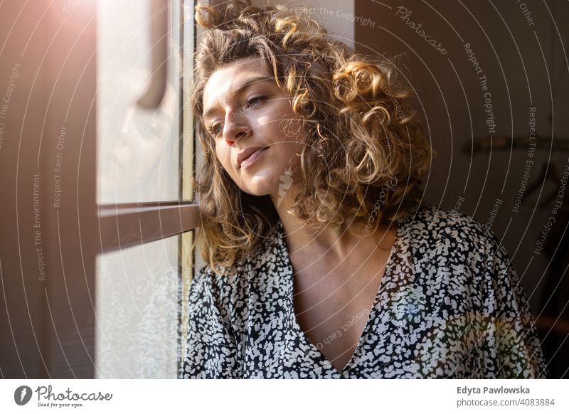 Junge Frau schaut aus dem Fenster Sperrung zu Hause bleiben COVID Coronavirus Pandemie Quarantäne soziale Distanzierung Krankheit Seuche Infektion Virus