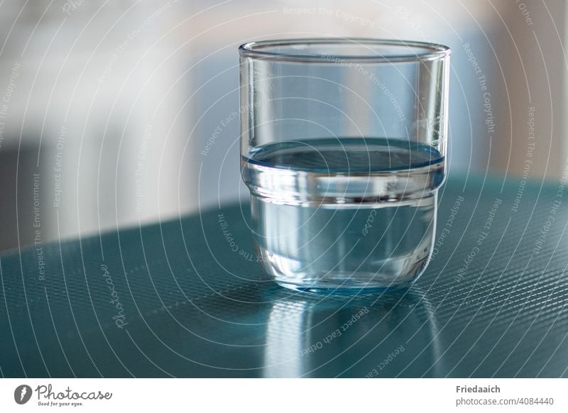 Wasserglas halb voll oder halb leer Glas Getränk Flüssigkeit blau zu Hause trinken minimalistisch Lichtspiel unscharfer Hintergrund frontal Nahaufnahme