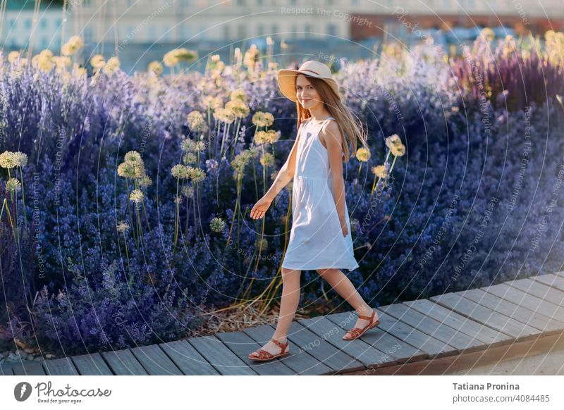 Lächelndes kleines Mädchen in weißem Kleid und Hut Spaziergang im lavendelfarbenen Stadtpark Kindheit violett Sommer Sonne niedlich Kleinkind Glück Spaß spielen