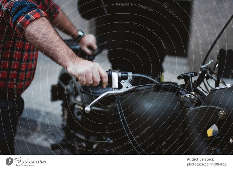 Crop Mann hält Motorrad auf Parkplatz in der Stadt Großstadt Asphalt urban Fahrzeug Verkehr reisen Straße modern schwarz Mitfahrgelegenheit Ausflug Reise Boden