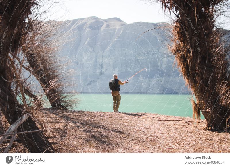 Mann Angeln in der Nähe von See Fischen Natur Stab Freizeit Wasser Aktivität Hobby Lifestyle Küste fangen Erholung Teich Berge u. Gebirge sonnig tagsüber