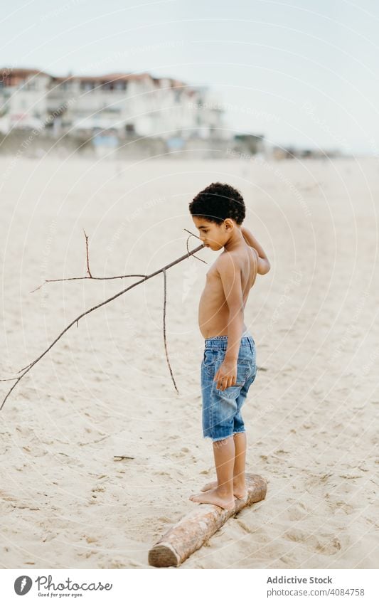 Anonymes schwarzes Kind, das auf einem Baumstamm läuft Beine laufen Totholz Sand Sommer Strand Barfuß wenig nass Lifestyle Freizeit ruhen sich[Akk] entspannen