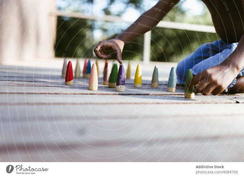 Crop schwarzes Kind spielt mit Kegeln Junge Spielen Sitzen sonnig tagsüber ohne Hemd farbenfroh Lifestyle Freizeit ruhen sich[Akk] entspannen Afroamerikaner