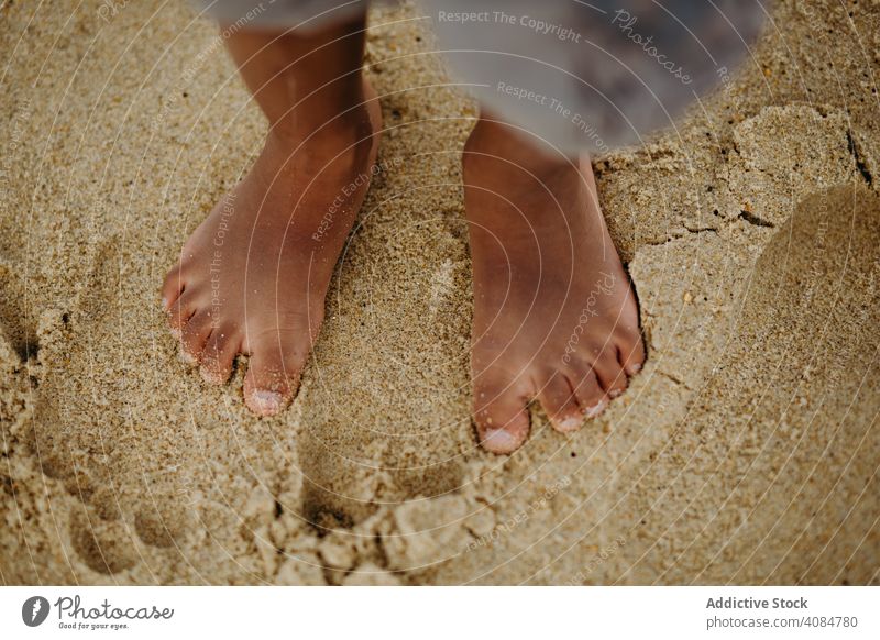Crop schwarzes Kind stehen auf Sand Beine Sommer Strand Barfuß wenig nass Lifestyle Freizeit ruhen sich[Akk] entspannen ethnisch Afroamerikaner Urlaub Ufer