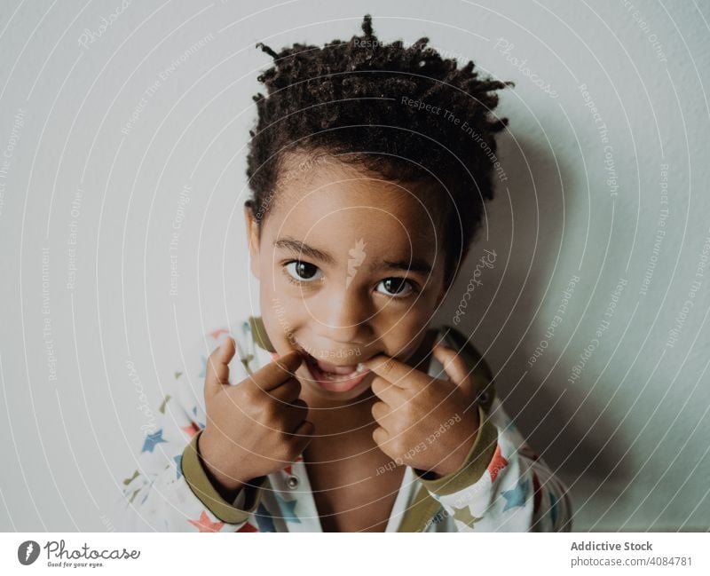 Schwarzes Kind, das für die Kamera Grimassen schneidet Junge lustig Afroamerikaner Pyjama Gesicht Ausdruck wenig Freude heiter Glück niedlich bezaubernd süß