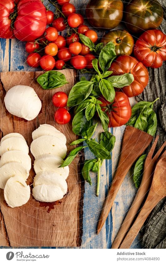 Salatzutaten auf Brett und Serviette Tomaten Käse Basilikum Holzplatte Salatbeilage Mozzarella Blätter frisch reif Zutaten Lebensmittel Mahlzeit Küche