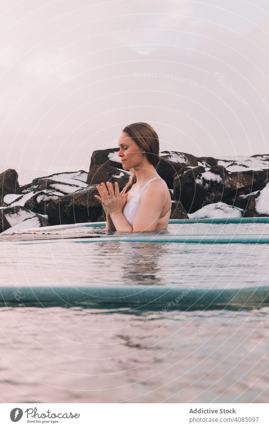 Frau sitzt im Pool in der Nähe von Steinen jung aussruhen Wasser geschlossene Augen Felsen Himmel wolkig Sommer Körper Erholung Gesundheit Natur Freizeit