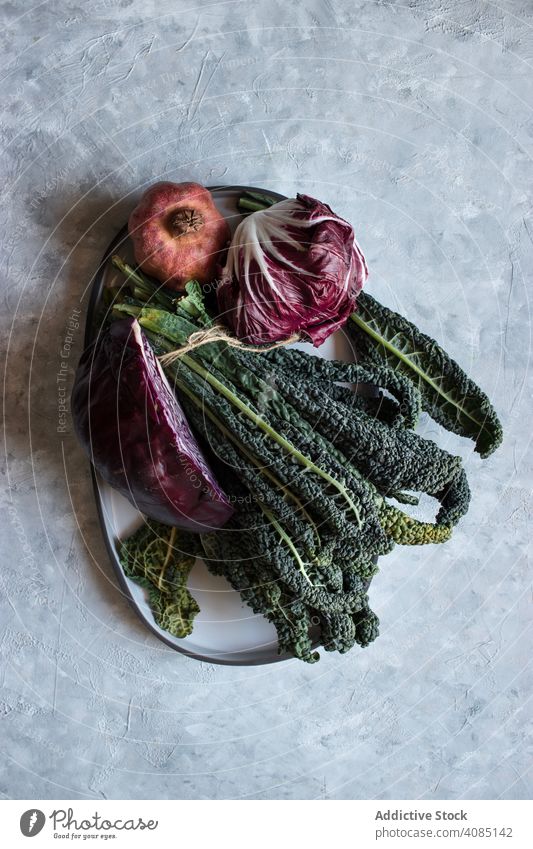 Granatapfel bei Rotkohl und Grünkohl Kale Kohlgewächse Teller Tisch Blätter rot Veganer Zutaten frisch Gemüse Frucht Gesundheit Salatbeilage roh organisch