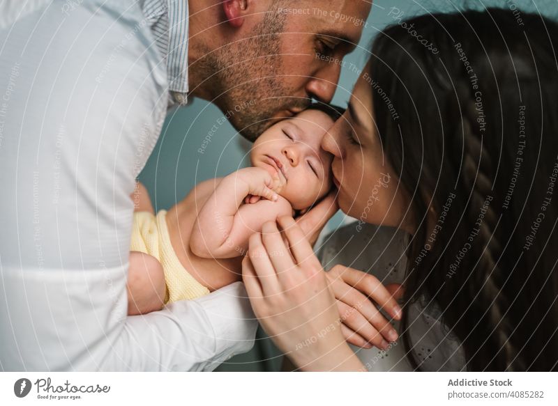 Eltern halten Baby im Zimmer Paar Kuss Küssen Beteiligung berührend Pflege Angebot Familie Liebe heimwärts Bonden Mann Frau Mutter Vater Zusammensein Freude