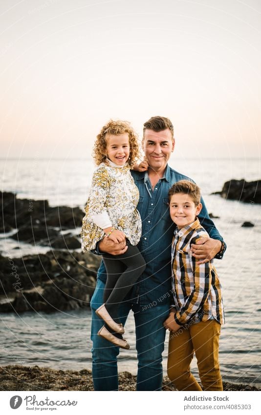 Vater mit ihren Kindern am Strand Familie Seeküste Urlaub Lächeln Umarmung umarmend Umarmen Mann mittleren Alters Tochter Sohn Mädchen